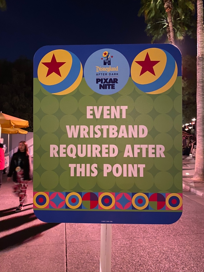 A sign that was posted in Pixar Pier in Disneyland California Adventure that tells guests that an event wristband is required after a point.