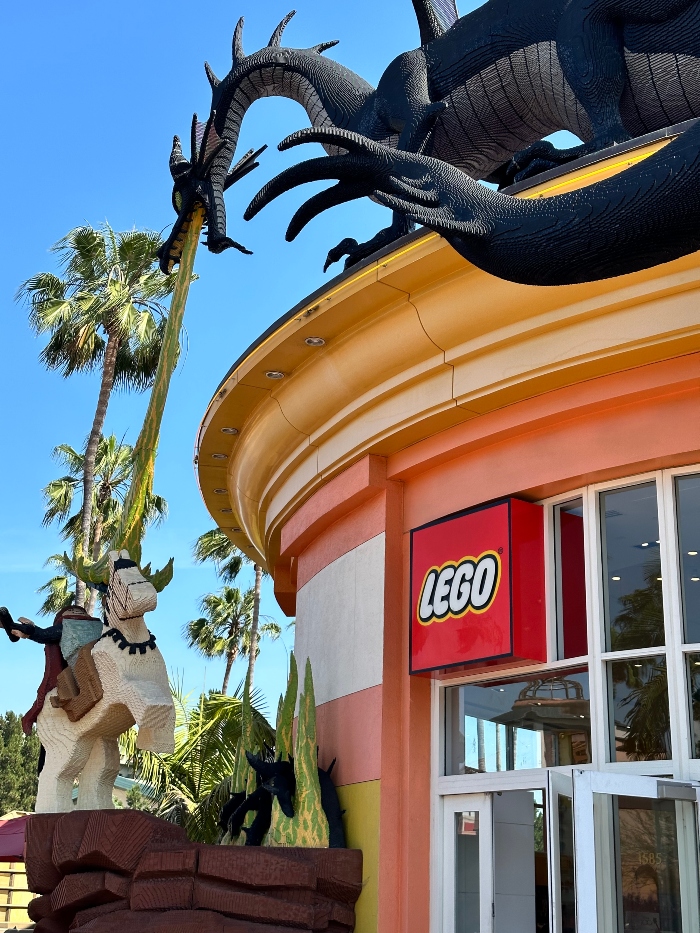 The front of the Lego Store at Downtown Disney District. A lego statue of the battle of Maleficent and Prince Philip in front of the store.