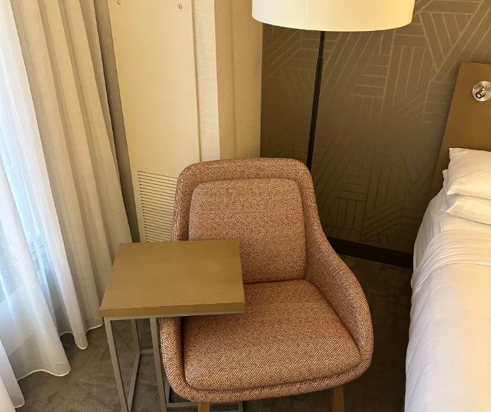 A chair next to one of the two queen-sized beds in the guest rooms at the Delta Hotels By Marriott.
